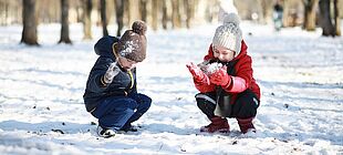 Zwei Kinder spielen in einem Park im Schnee