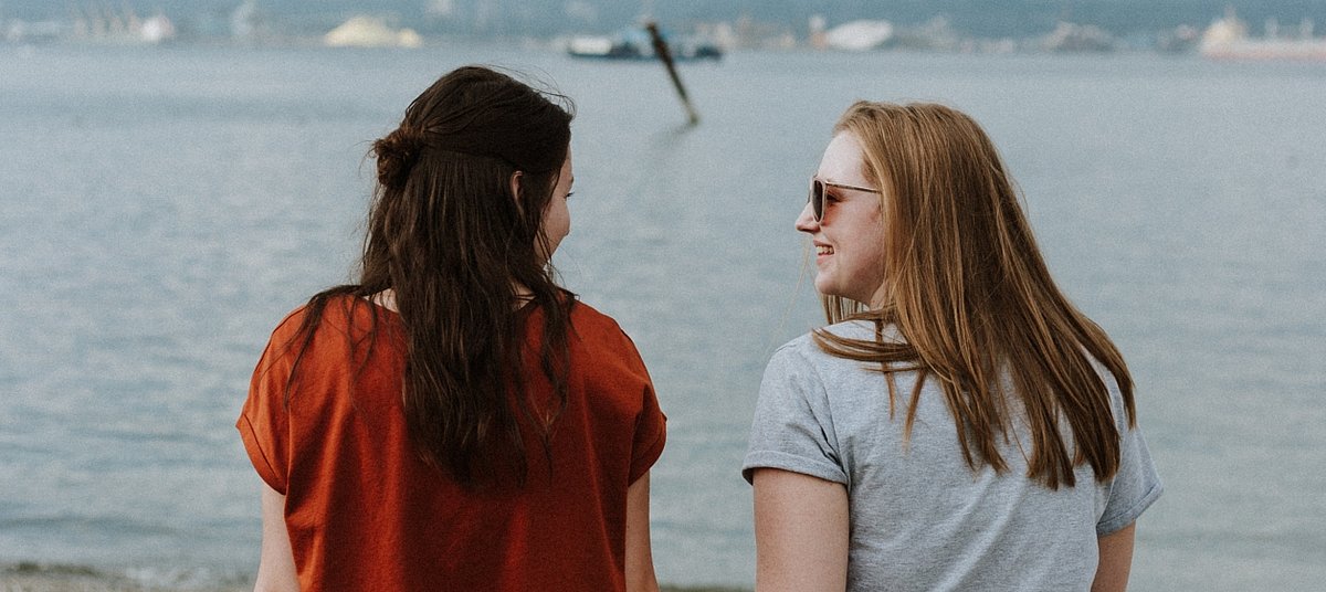 Zwei junge Frauen am Ufer eines Sees im Gespräch