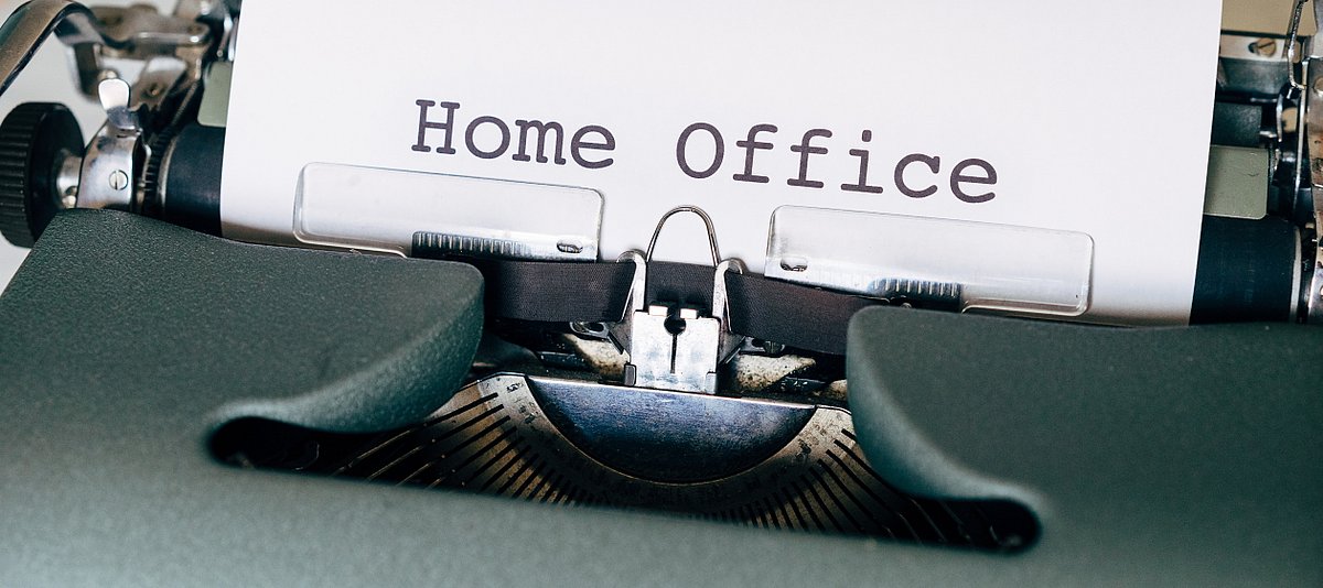 Eine alte Schreibmaschine, in der ein Blatt Paier eingespannt ist auf dem das Wort Home Office steht