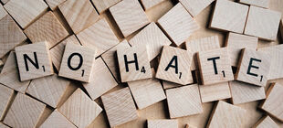 Holzplättchen mit Buchstaben formen die Worte "No Hate".