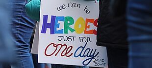 Schild mit der Aufschrift "We can be Heroes Just for one Day - David Bowie" in bunter Schrift