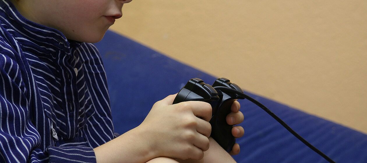 Ein Junge spielt per Controller mit einer Spielekonsole.