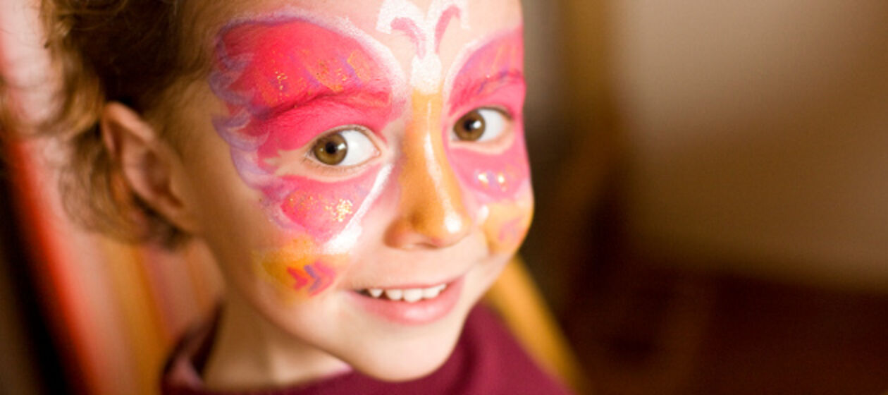 Einem Mädchen wurde ein großer Schmetterling ins Gesicht gemalt.