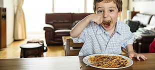 Ein Kind isst Spaghetti