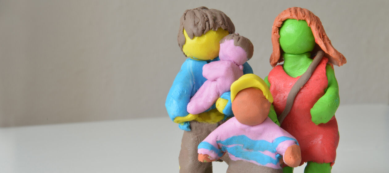 Bunte Figuren aus Knete, die eine Familie darstellen.