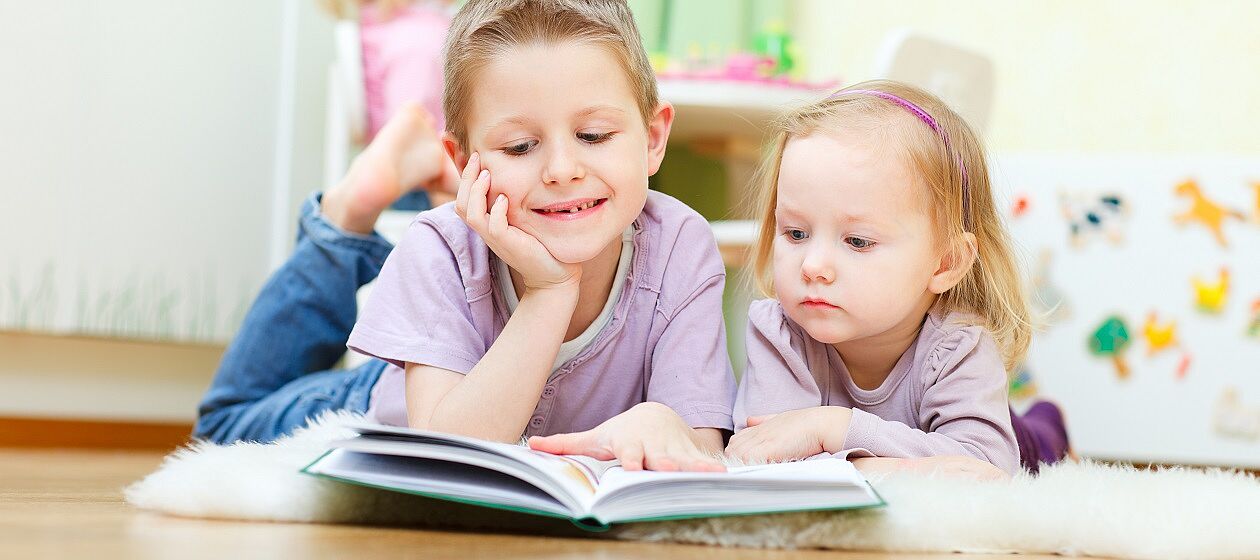 Ein Mädchen und ein Junge schauen sich gemeinsam ein Buch an.