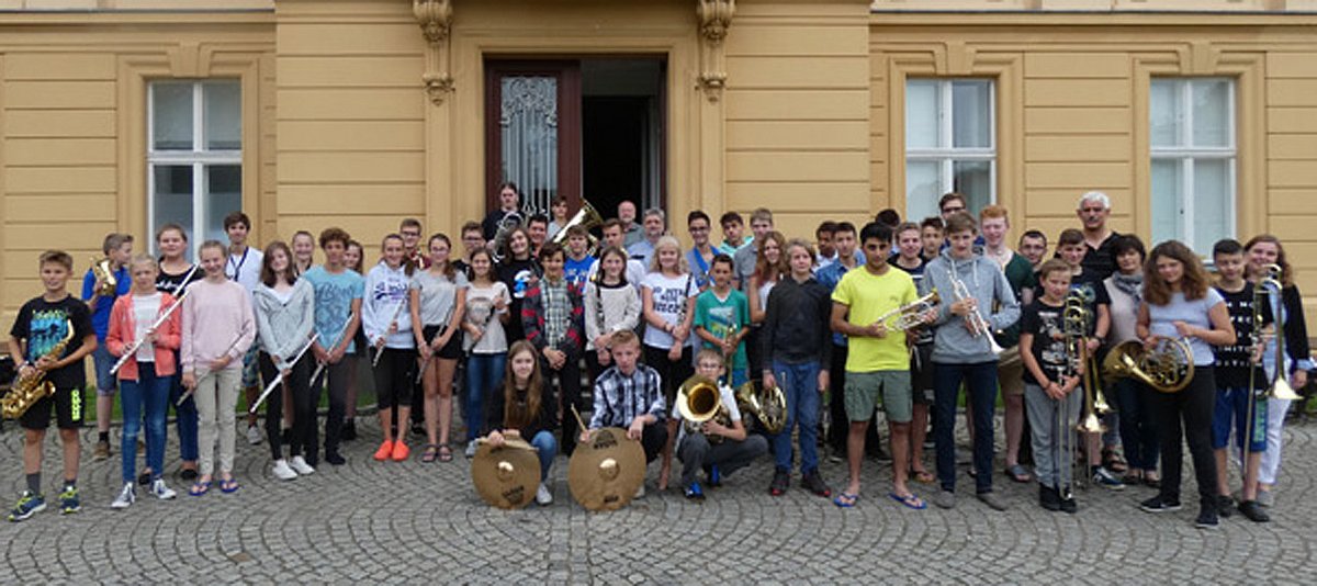 Die Teilnehmenden stehen mit ihren Musikinstrumenten vor dem Eingang zum Bildungs- und Begegnungszentrum Schloss Trebnitz. 