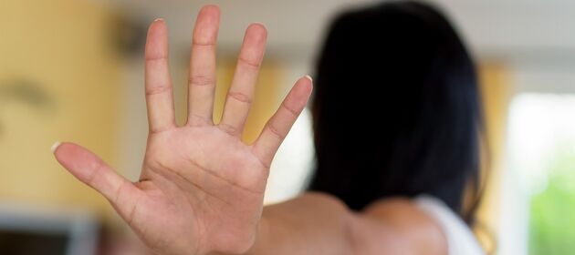Eine Frau hält ihren Arm ausgestreckt und zeigt symbolisch mit ihrer Hand "Stop! Aufhören!".