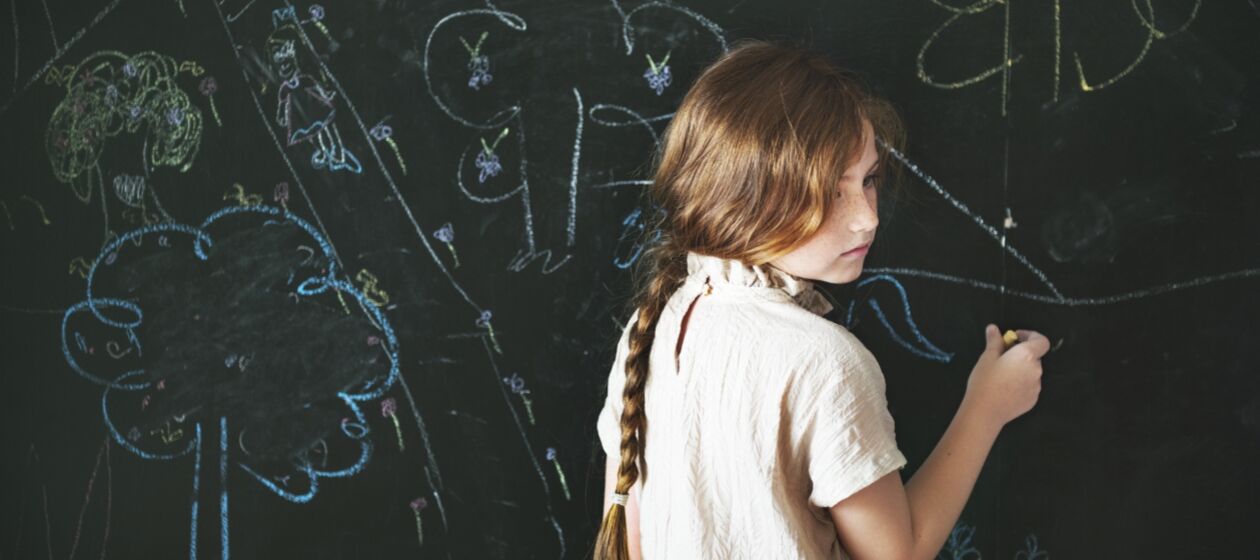 Mädchen malt an einer Tafel und schaut traurig zur Seite