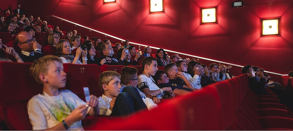 Junge Menschen sitzen im Kino und schauen gespannt auf die Leinwand.