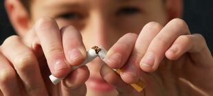Ein Jugendlicher bricht eine Zigarette in der Mitte durch
