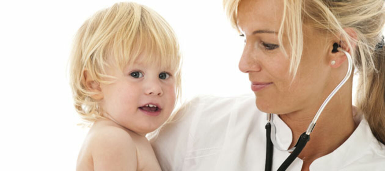 Eine Medizinerin mit einem kleinen Jungen auf dem Arm