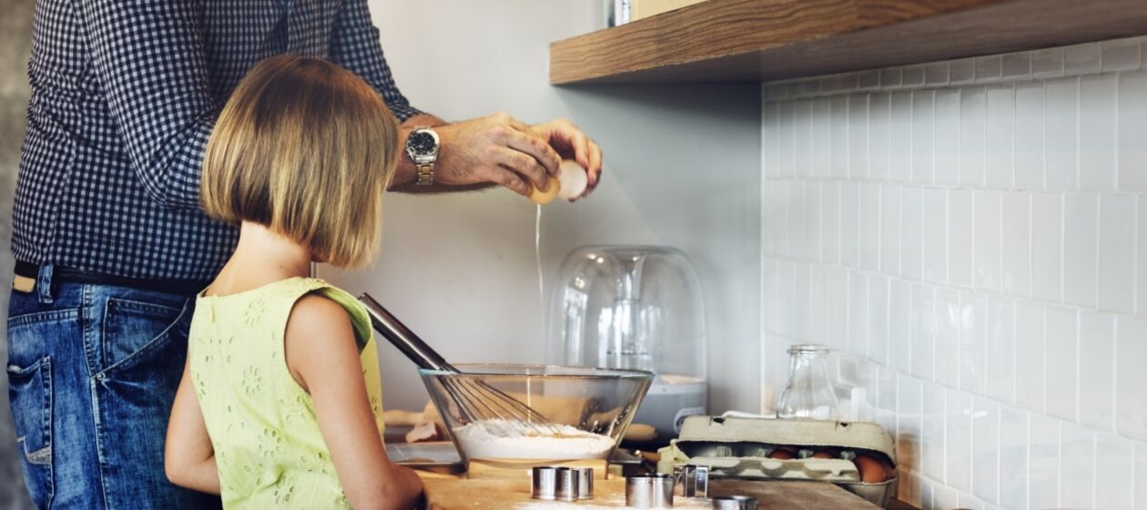 Ein Vater steht mit seiner Tochter in der Küche und backt Plätzchen