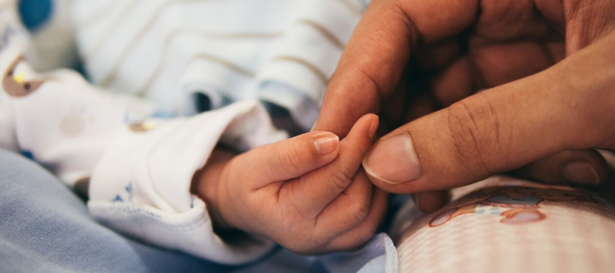 Nahaufnahme wie einer Mutter vorsichtig die kleinen Finger ihres Neugeborenen hält