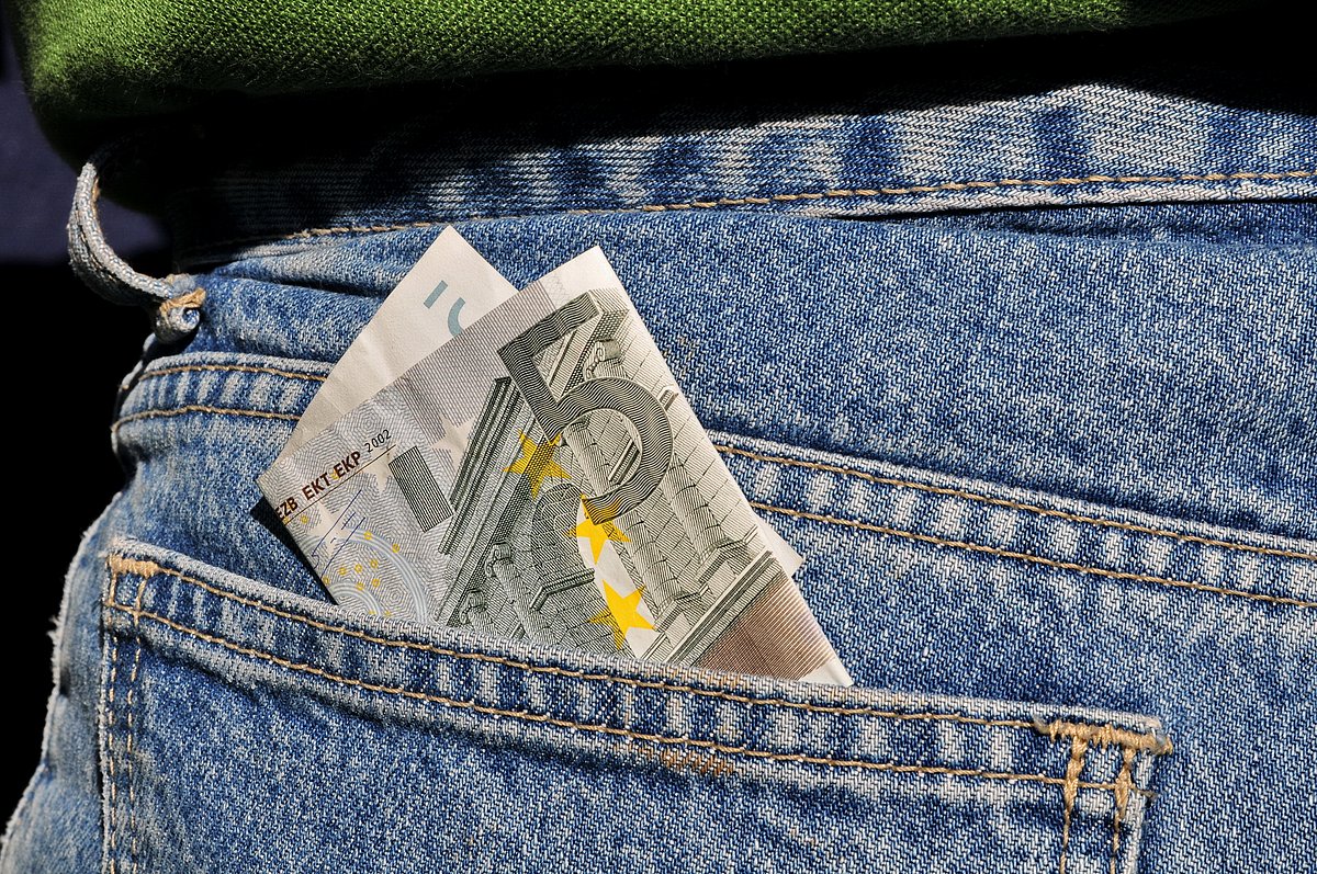 Fünf Euro stecken in der Tasche einer Jeans