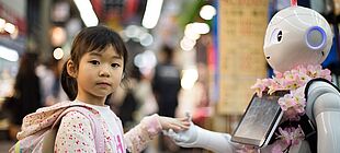 Ein Kind gibt einem Roboter die Hand