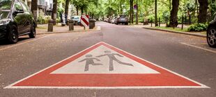 Leere Straße mit "Achtung Kinder" Markierung auf dem Asphalt