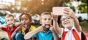 Vier Schulkinder machen ein Selfie mit einer Handykamera.