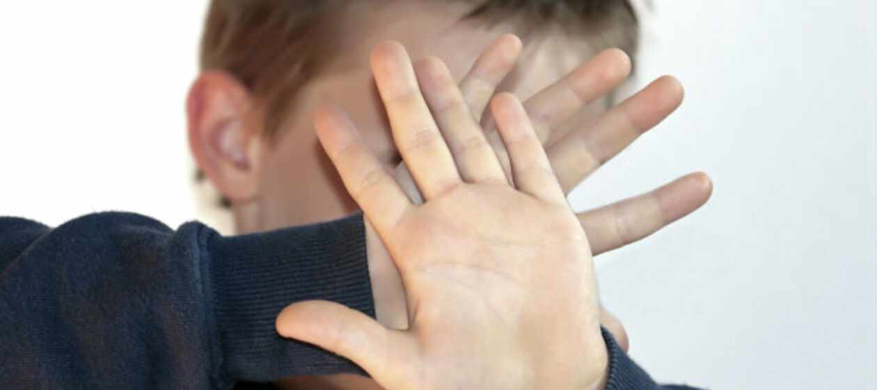 Kind hält Hände vors Gesicht
