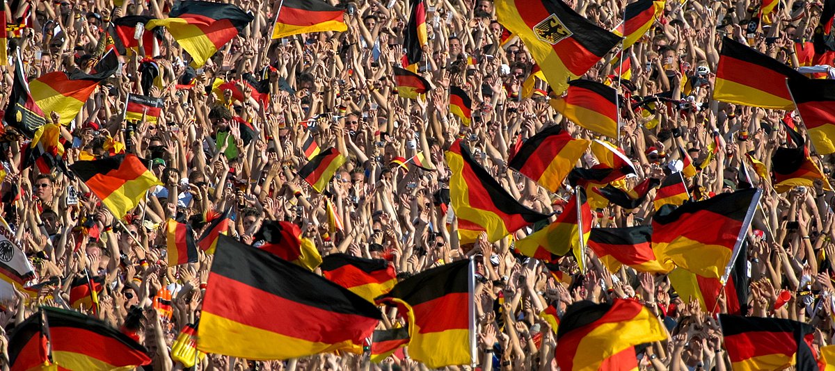 Jubelnde Menschenmenge mit vielen wehenden Deutschlandfahnen 