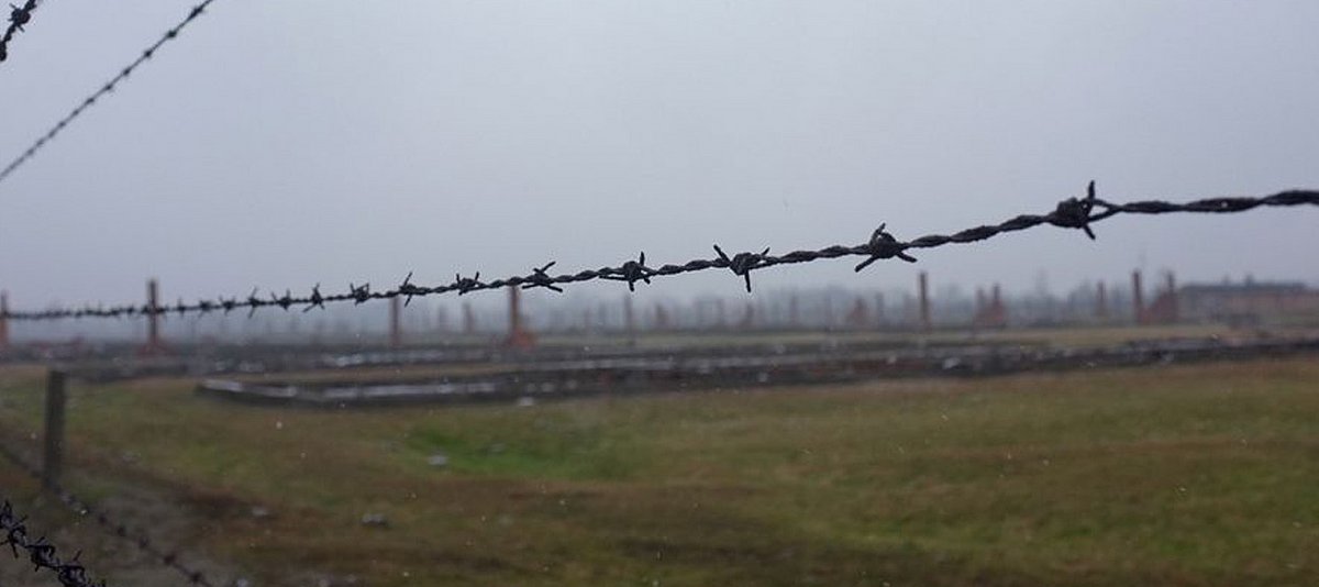 Gelände des KZ Auschwitz-Birkenau mit Stacheldraht und Baracken 