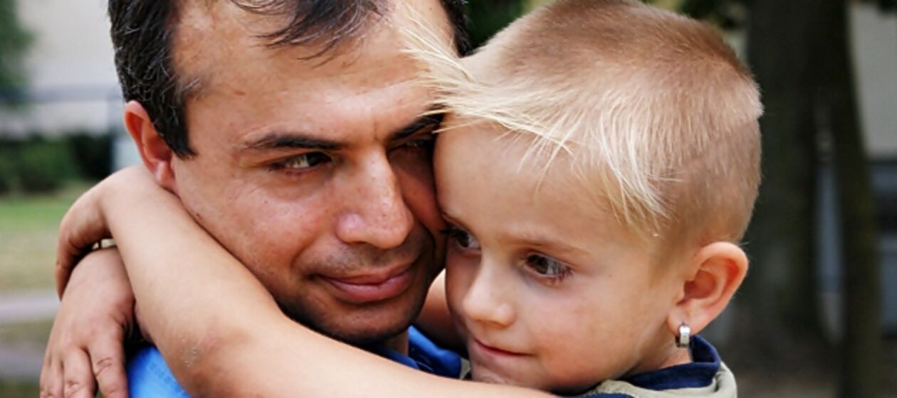 Ein Vater trägt seinen Sohn auf dem Arm.