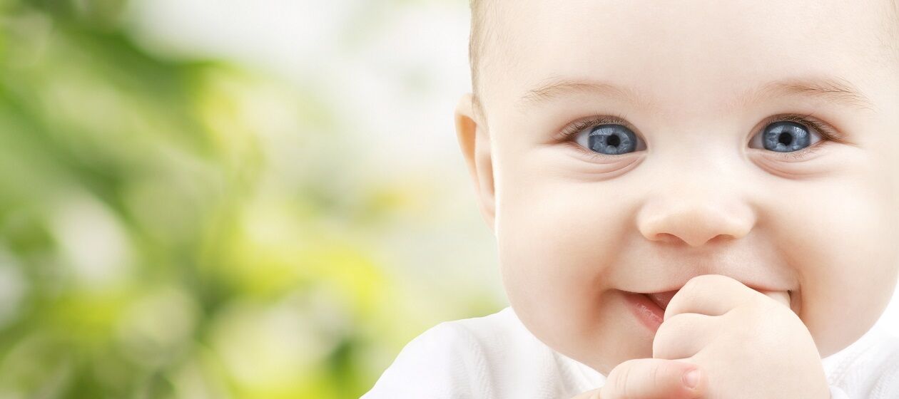 Säugling mit blauen Augen schaut in die Kamera und lacht
