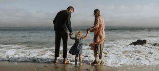 Zwei Erwachsene und ein Kind stehen am Strand