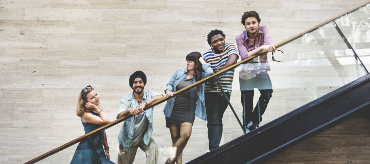 Fünf junge Menschen stehen in einer Reihe auf einer Treppe 