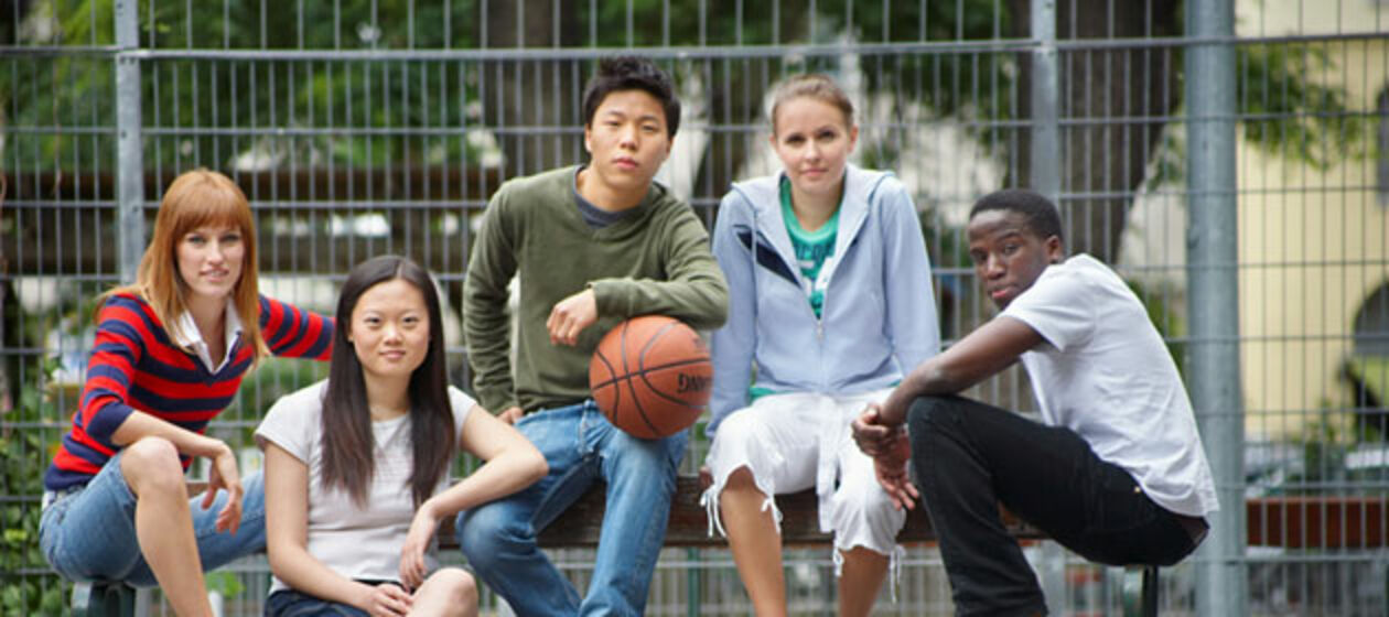 Jugendliche unterschiedlicher Hautfarbe sitzen auf einer Bank