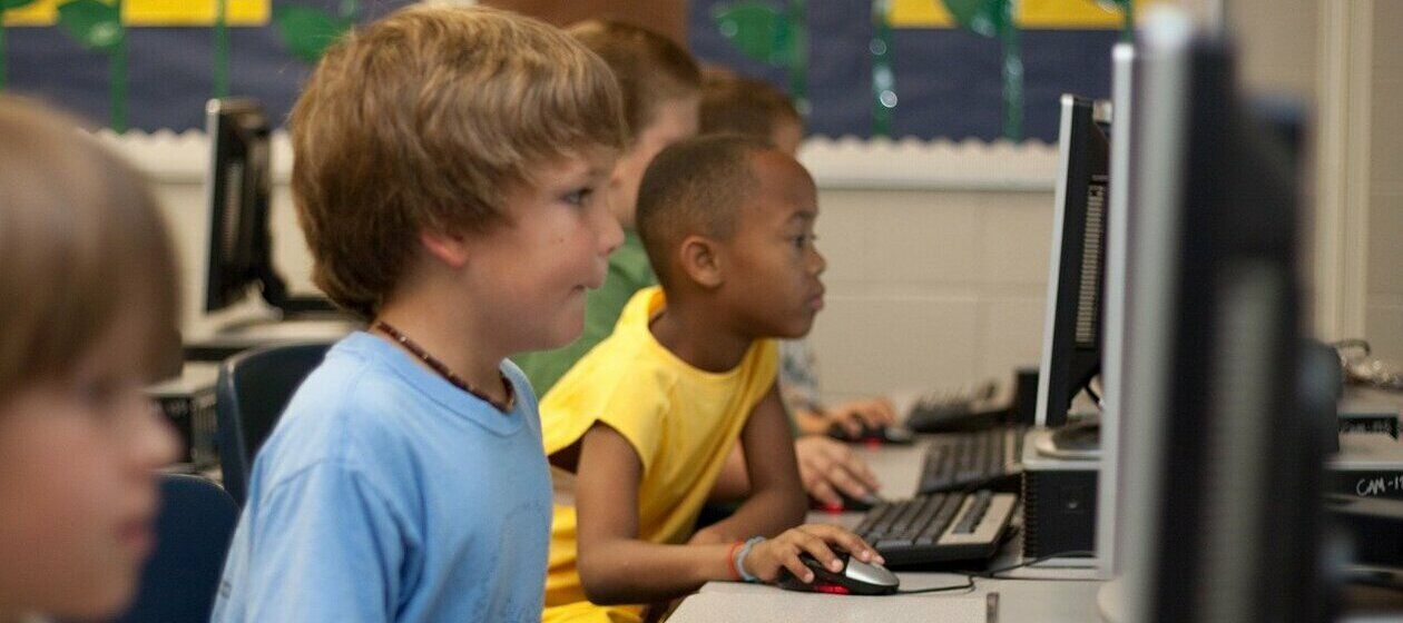 Eine Reihe Fünftklässler sitzt im Schulunterricht konzentriert an PCs