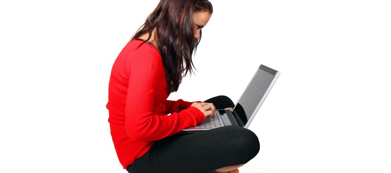 Mädchen sitzt mit Laptop auf dem Schoß