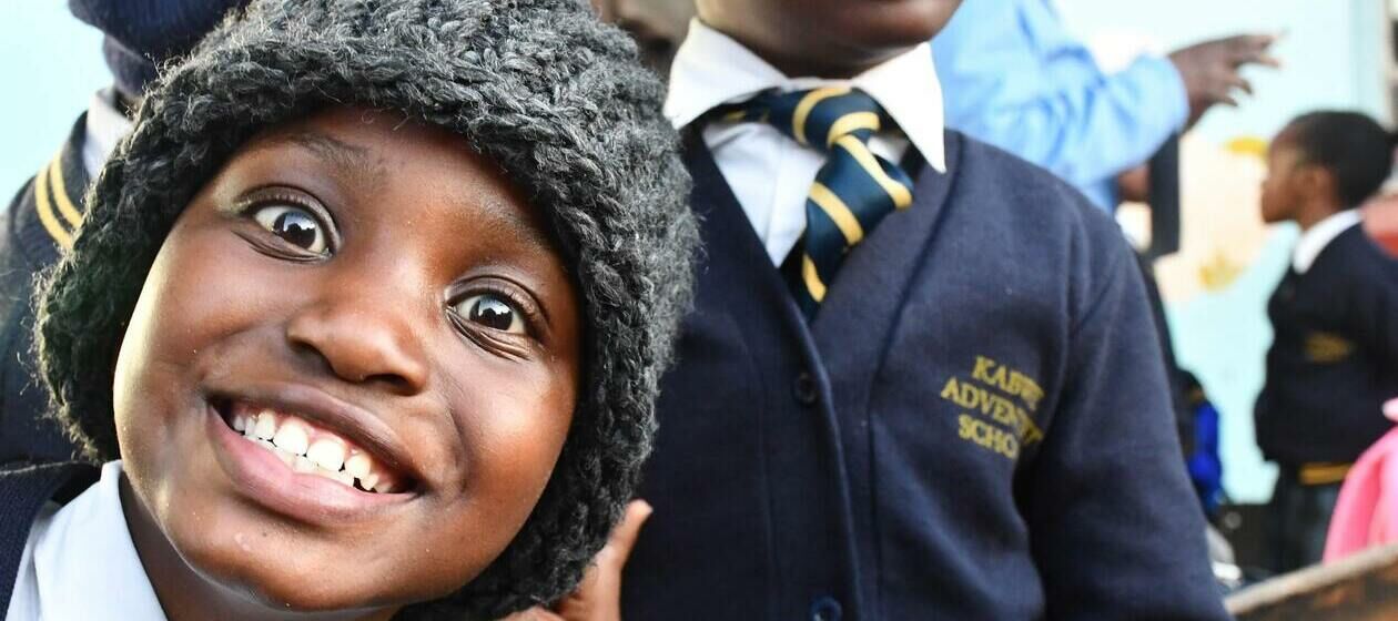 Ein afrikanischer Junge in Schuluniform lächelt in die Kamera.