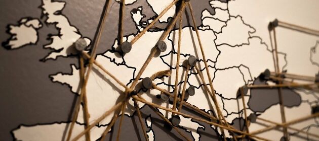 Auf einer Europakarte sind mit Pins und Schnüren Netzwerke gespannt
