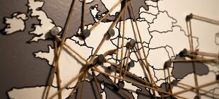 Auf einer Europakarte sind mit Pins und Schnüren Netzwerke gespannt