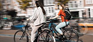 Zwei junge Frauen fahren auf Fahrrädern durch die Stadt