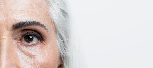 Auge einer älteren Frau mit langen weißen Haaren 