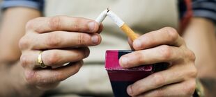 Ein Mann bricht eine Zigarette in zwei Stücke