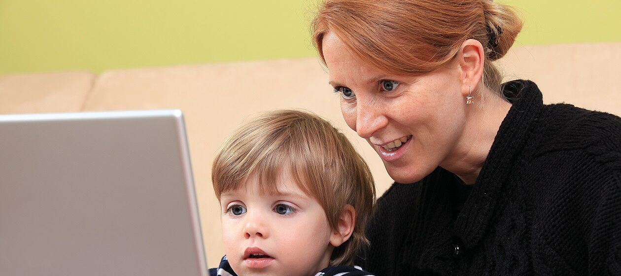 Eine Mutter sitzt mit ihrem kleinen Sohn am Laptop.