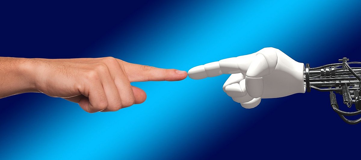 Eine Menschenhand und eine Roboterhand berühren sich mit einem Finger
