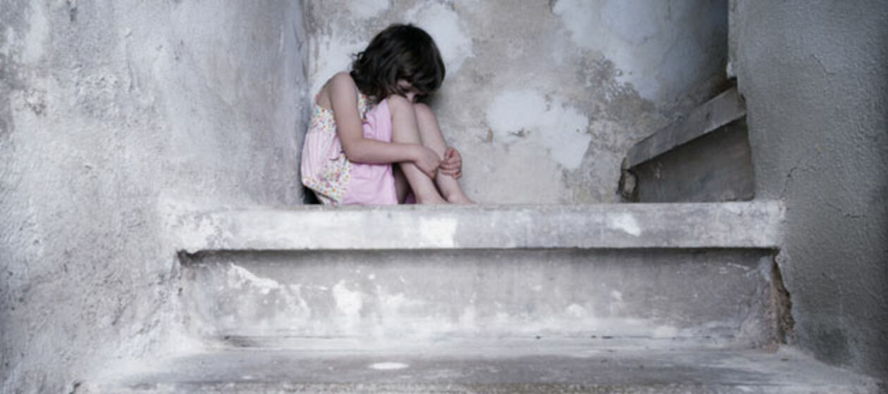 Ein Kind sitzt traurig in einer Ecke