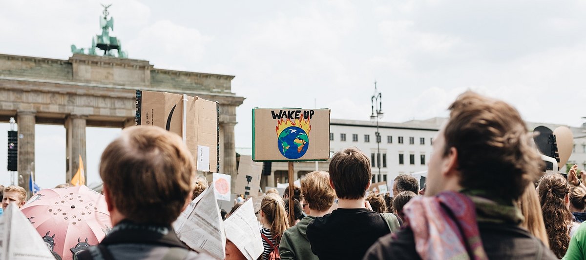Junge Demonstranten marschieren mit selbstgemalten Schildern auf das Brandenburger Tor zu