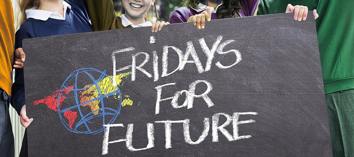 Auf einem Schild, das von mehreren jungen Menschen gehalten wird, steht Fridays for Future
