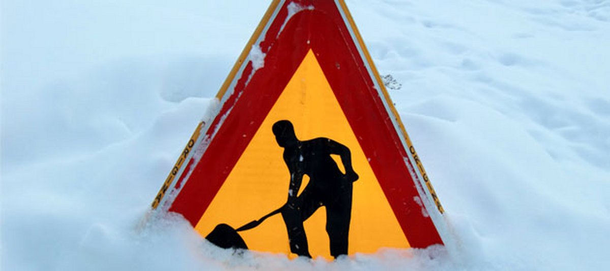 Ein im Schnee fast versunkenes Schild, dass auf Arbeiter hinweist