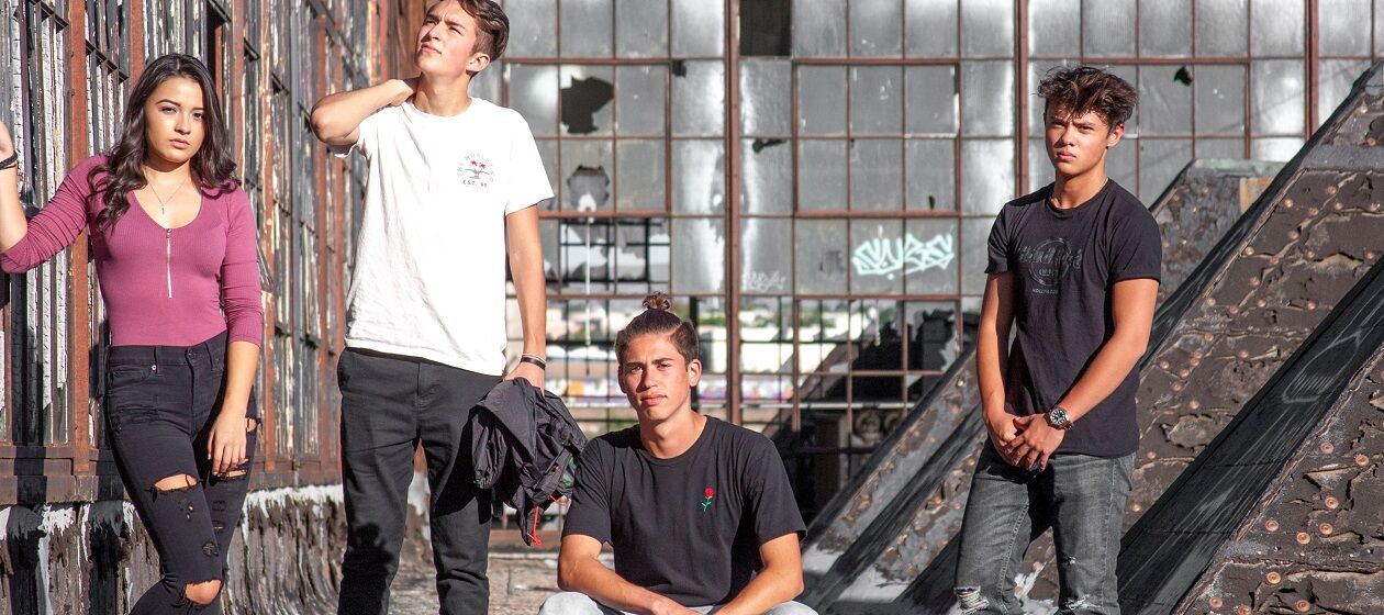 Vier Jugendliche, davon ein Mädchen, posieren in einem heruntergekommenen Gebäude fürs Foto.