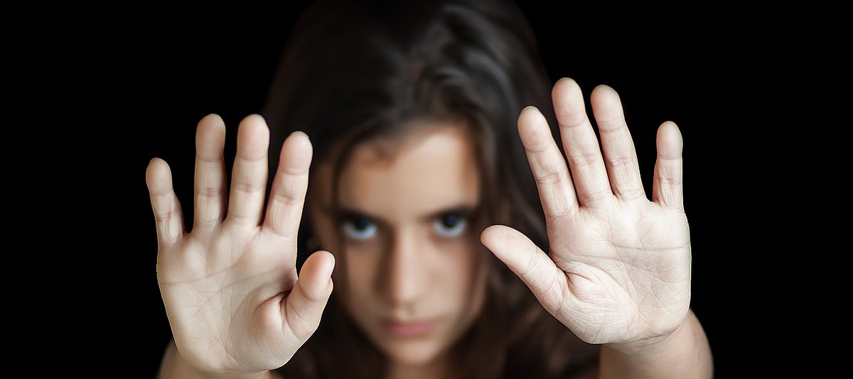 Eine junge Frau hält beide Hände abwehrend vor sich