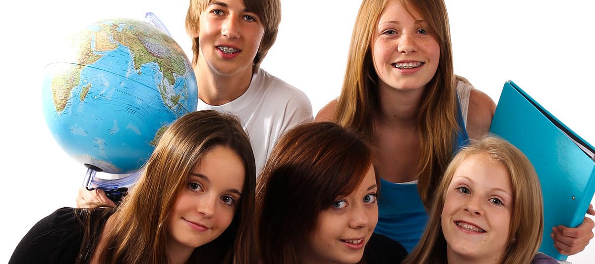 Fünf Teenager halten lächeln einen Schulordner und einen Globus.