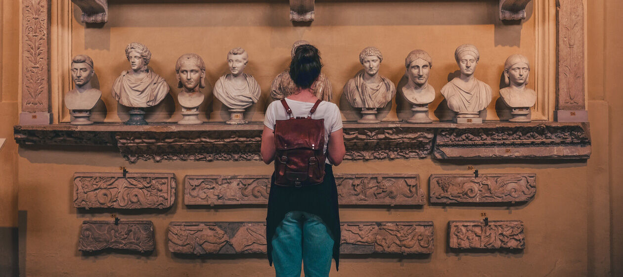 Junge Frau steht in einem Museum vor Statuen