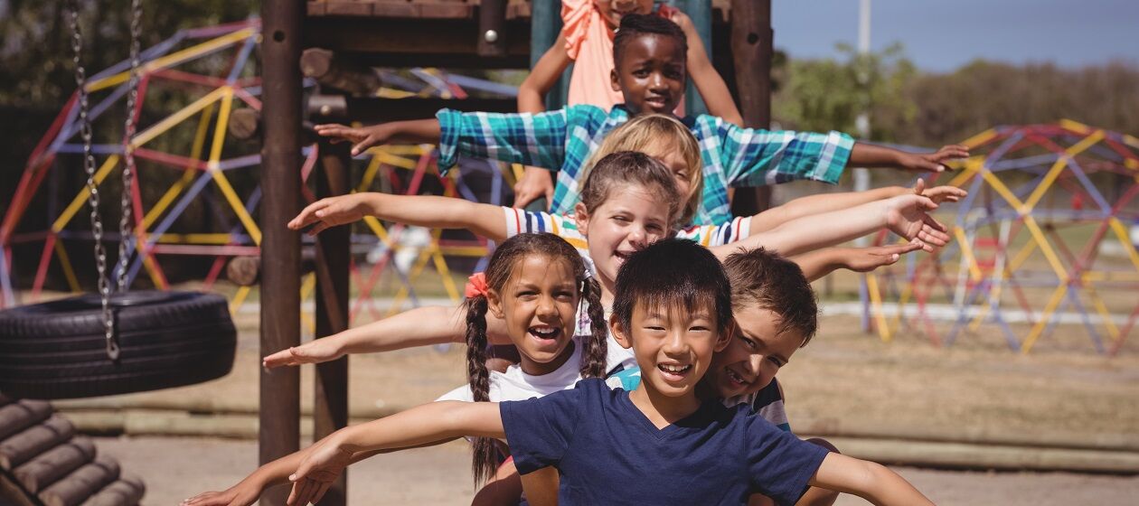 Eine Gruppe Kinder posiert hintereinander auf einem Spielplatz
