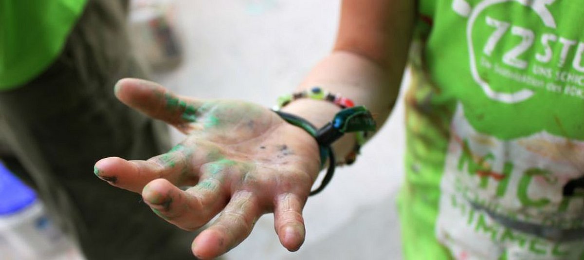 Ausgestreckte Hand einer Jugendlichen mit Farbklecksen
